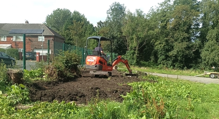 Levelling ground with a digger at Deane & Derby Cricket Club Community Garden